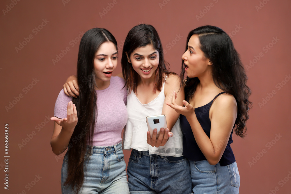 Three Fashionable Ladies Are Looking Into Their Phone And Smiling Three Fashionable Ladies Are Looking Into Their Phone And Smiling