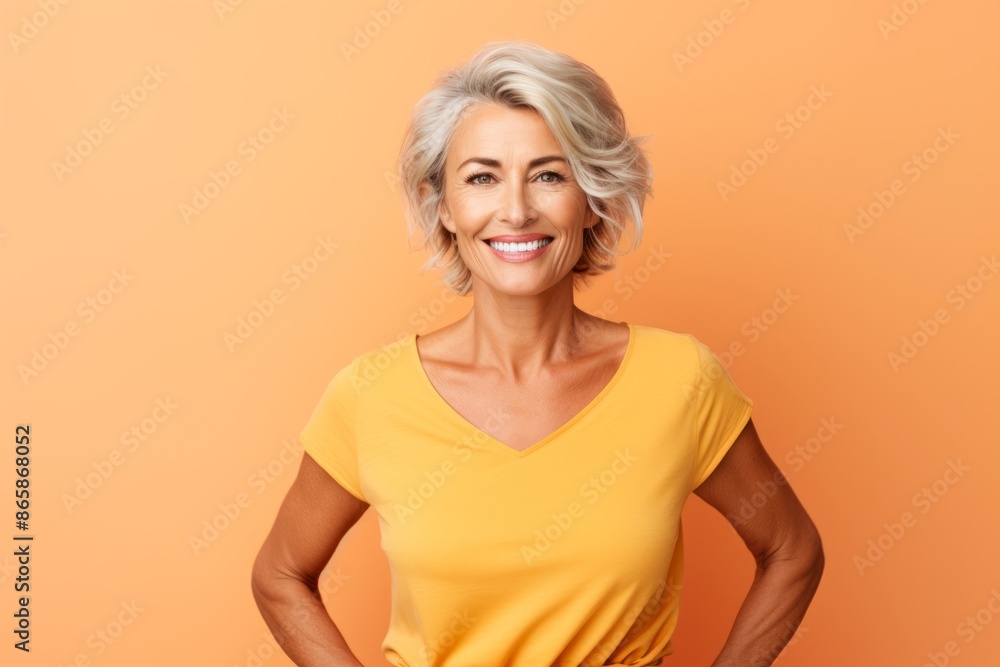 Portrait of happy mature woman in yellow t-shirt on orange background Portrait of happy mature woman in yellow t-shirt on orange background