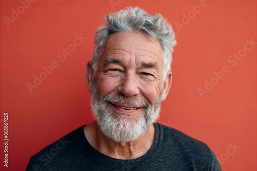 Senior man with white beard and grey t-shirt on red background