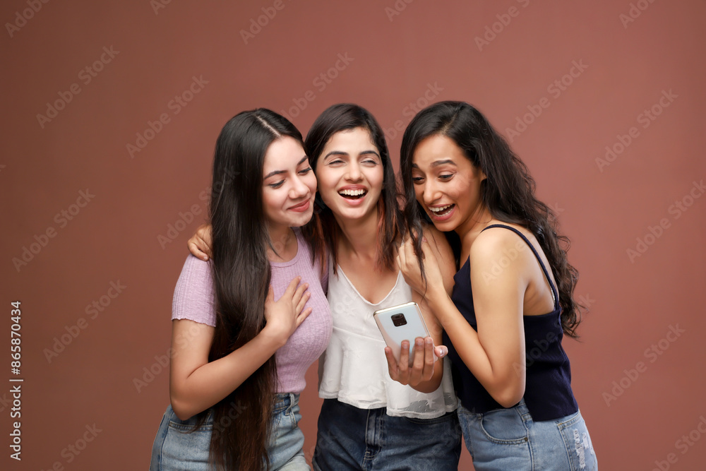 Three Naughty Ladies Are Smiling And Looking Into Phone While Standing Three Naughty Ladies Are Smiling And Looking Into Phone While Standing