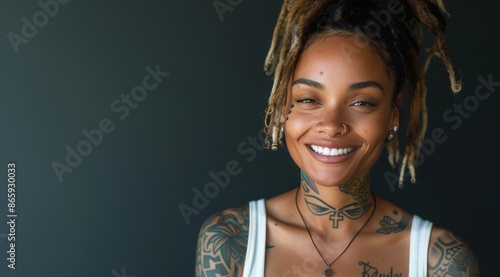 Portrait of a Smiling Woman With Dreads and Tattoos Against a Dark Background