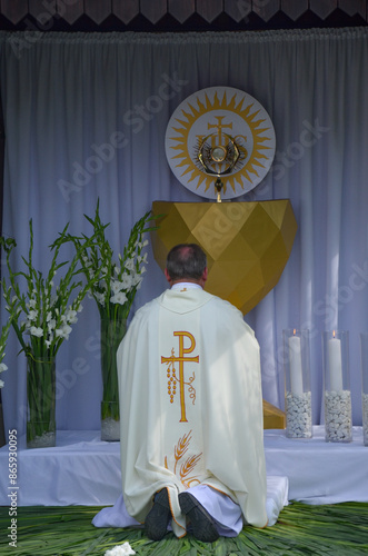 A priest kneels in front of the altar during the Corpus Christi procession