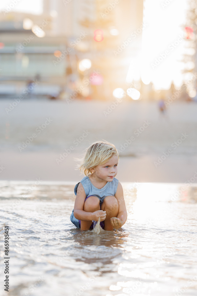 Child playing in shallow water on Gold Coast beach in golden afternoon light Child playing in shallow water on Gold Coast beach in golden afternoon light