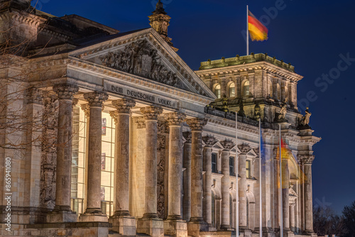 Photography The entrance portal of the Reichstag in Berlin with german flags at night