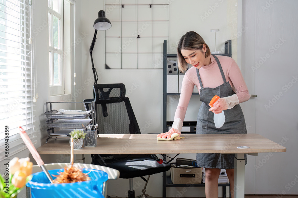 Obraz premium Professional Maid Cleaning Office Desk in Modern Home Office Setting with Natural Light and Organized Workspace