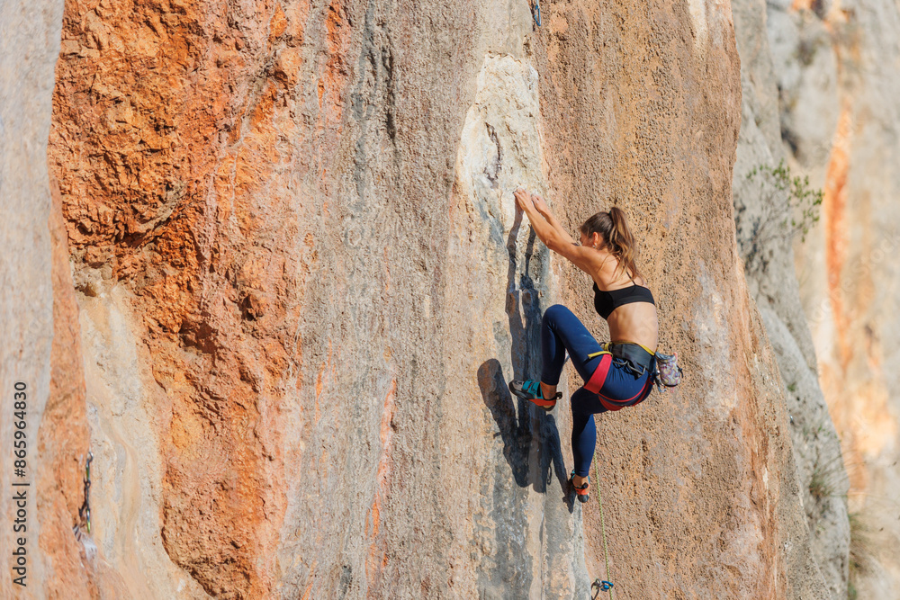 The girl climbs the rock. The climber is training to climb the rock. A strong athlete overcomes a difficult climbing route. Extreme hobby. . The girl climbs the rock. The climber is training to climb the rock. A strong athlete overcomes a difficult climbing route. Extreme hobby. .
