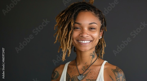 Portrait of a Smiling Woman With Dreads and Tattoos Against a Dark Background