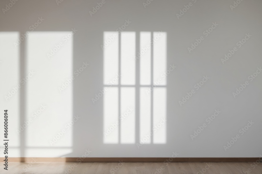 Obraz premium Sun casts light shadow patterns on empty room from window onto white wall