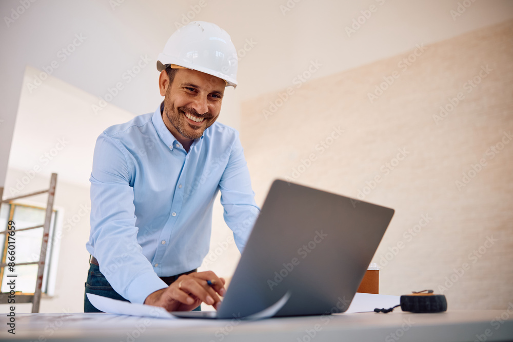 Happy architect using laptop while working on home renovating project Happy architect using laptop while working on home renovating project