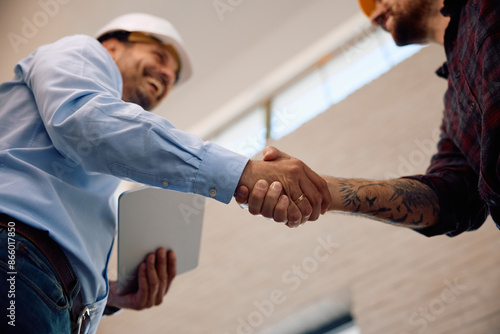 Photos Close up of building contractor shaking hands with worker at construction site