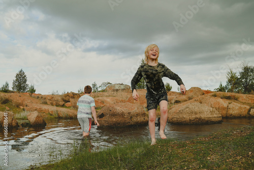 Two boys swimming  fully clothed waterhole in Australian bush
