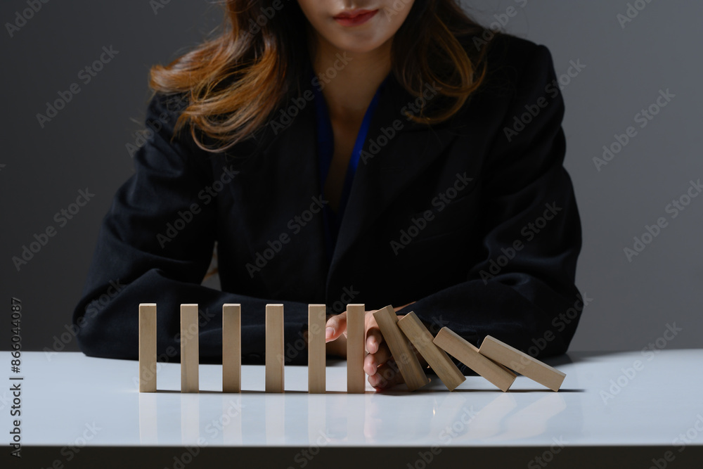 Businessperson hand stopping falling wooden blocks. Financial risk management, prevention and development to stability Businessperson hand stopping falling wooden blocks. Financial risk management, prevention and development to stability