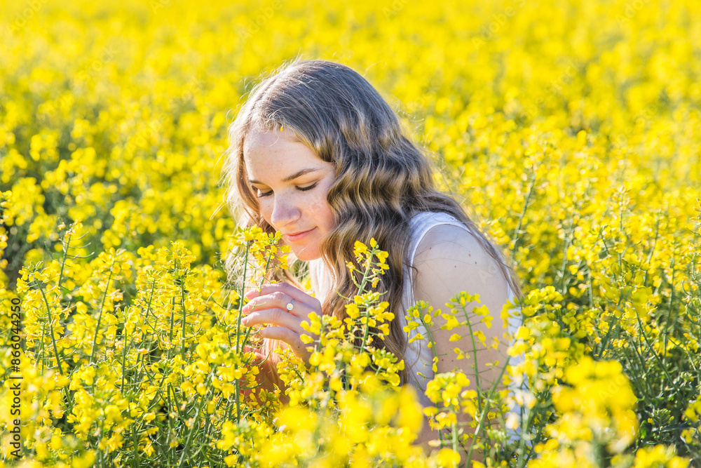 Teenage girl smelling canola flowers in paddock on farm Teenage girl smelling canola flowers in paddock on farm
