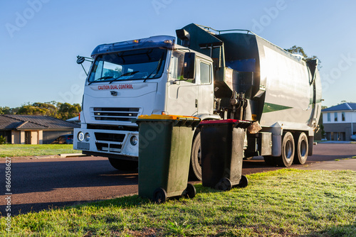 Recycling truck picking up bin from suburban roadside