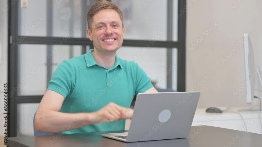 Casual Young Man with Thumbs Up Looking at Camera while Working on Laptop Casual Young Man with Thumbs Up Looking at Camera while Working on Laptop