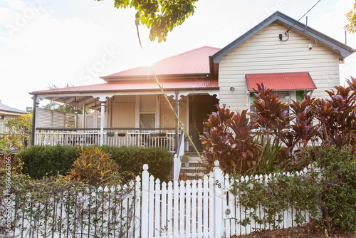 old Queenslander style house in Brisbane suburbs with an overgrown garden on a sunny day photo