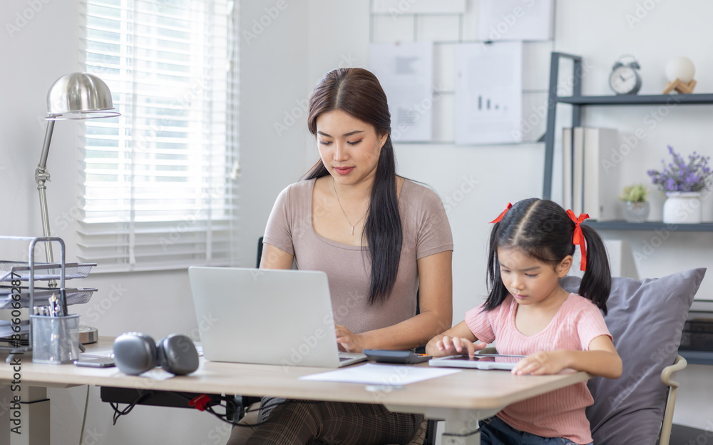 Asian business lady working on computer while her daughter hugging her Asian business lady working on computer while her daughter hugging her