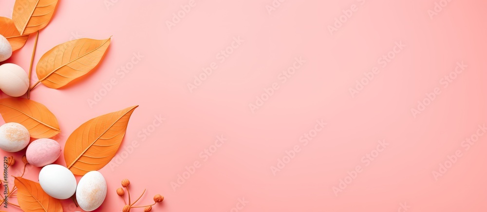 Fototapeta premium Easter-themed flat lay with an orange leaf and painted eggs on a pink background, offering copy space image.