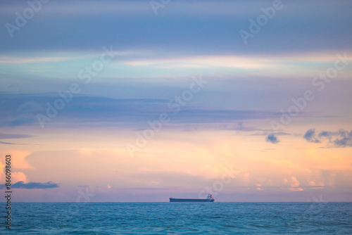 Cargo ship lined up at sea en route to Newcastle Harbour under a vibrant sunset sky