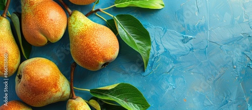 Fresh pears and green leaves displayed on a blue backdrop with copy space image.