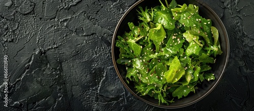 Overhead view of a Hiyashi Wakame Chuka Salad in a delivery box, isolated on a black background, featuring a text and copy space image for an advertising banner, garnished with sesame seeds. photo