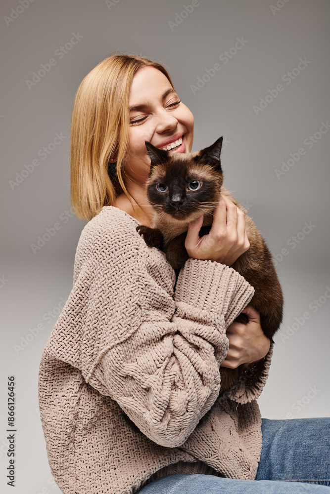 A woman with short hair sits on the floor, gently holding her cat in a peaceful and loving moment at home. A woman with short hair sits on the floor, gently holding her cat in a peaceful and loving moment at home.