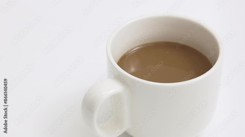 A drop of coffee falling into a cafe latte in a white coffee cup. White background, Slow motion A drop of coffee falling into a cafe latte in a white coffee cup. White background, Slow motion