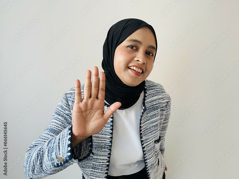 Portrait shot of young Asian Muslim young happy charming female model in casual clothing and hijab smiling hold hand up greeting say hello hi on white background. Portrait shot of young Asian Muslim young happy charming female model in casual clothing and hijab smiling hold hand up greeting say hello hi on white background.