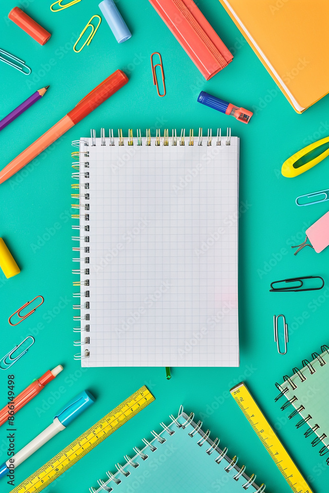A blank notebook placed amidst stationery items like rulers, pens, and erasers in a flat lay arrangement on a green isolated background, providing ample text space. A blank notebook placed amidst stationery items like rulers, pens, and erasers in a flat lay arrangement on a green isolated background, providing ample text space.