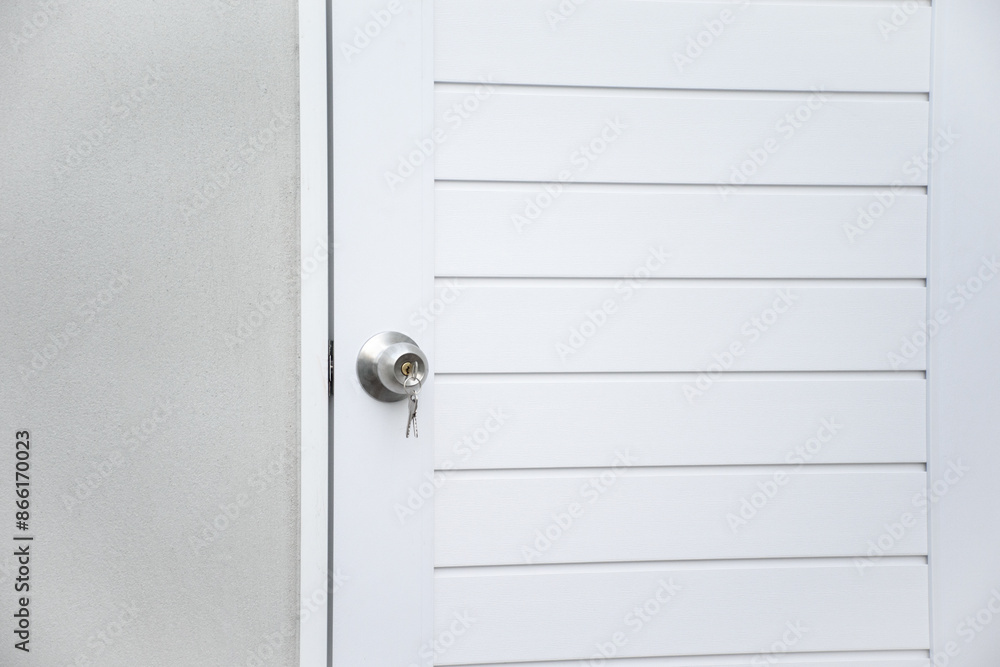 Fototapeta premium Modern white wooden door with silver knob and keys against gray concrete background for forgot to close the door or lost the key and safety with security concept.