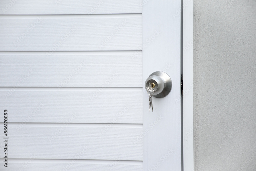 Close up modern white wooden door with silver knob and keys against gray concrete background for forgot to close the door or lost the key and safety with security concept. Close up modern white wooden door with silver knob and keys against gray concrete background for forgot to close the door or lost the key and safety with security concept.