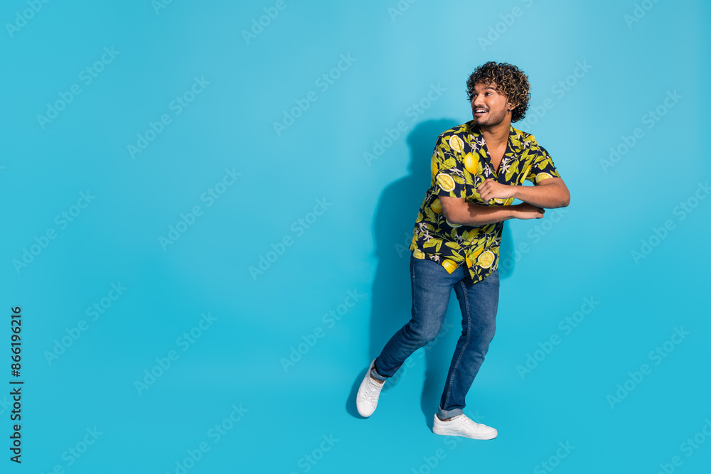 Full size photo of overjoyed handsome man dressed print shirt jeans dancing look at sale empty space isolated on blue color background Full size photo of overjoyed handsome man dressed print shirt jeans dancing look at sale empty space isolated on blue color background