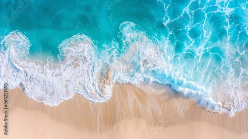 Aerial view of vibrant blue waves meeting the beach, creating a beautiful contrast with the beige sand