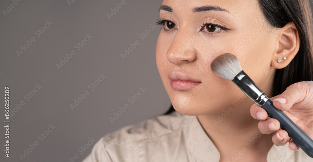 Makeup concept. Cosmetic Powder Brush near asian female face. Make-up closeup. Makeup concept. Cosmetic Powder Brush near asian female face. Make-up closeup.