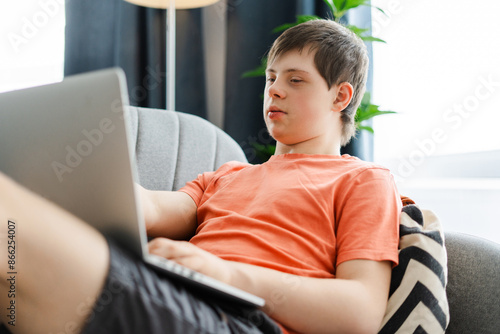 Young man with down syndrome using laptop computer at home photo