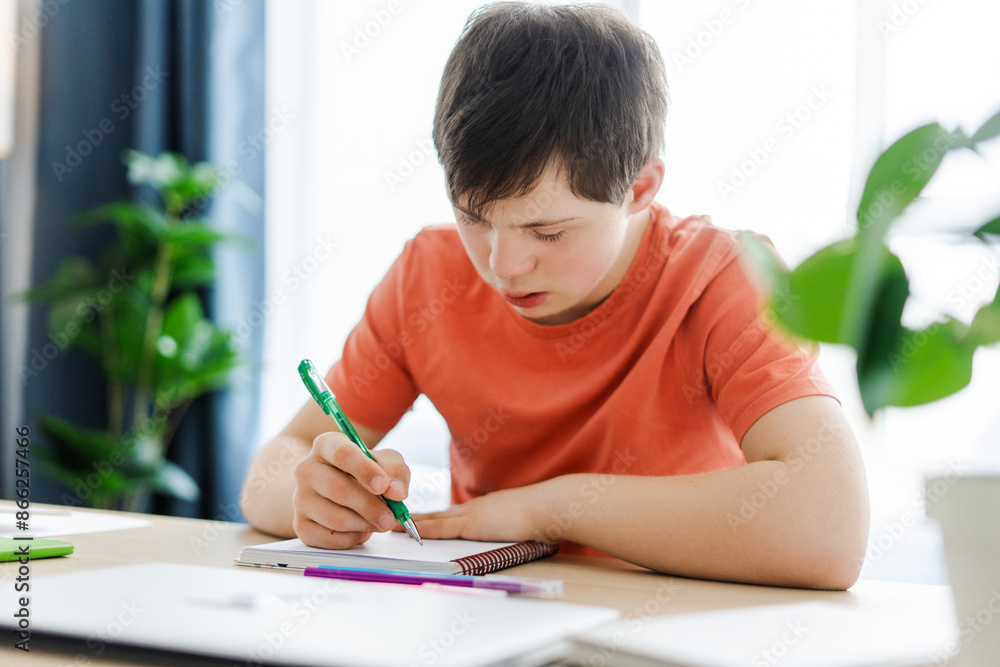 Teenager with down syndrome doing homework at home concentrating on studying Teenager with down syndrome doing homework at home concentrating on studying