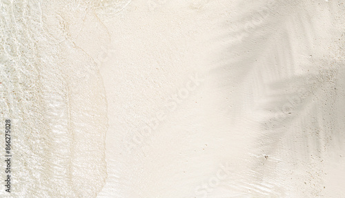 Fototapeta Naklejka Na Ścianę i Meble -  Palm leaf shadow on abstract untouched sand beach background with sunlight in transparent water waves, view from above