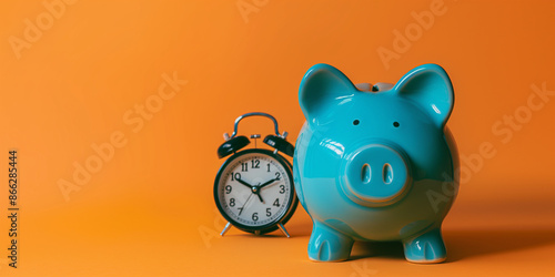 Charming cyan piggy bank on a solid orange background next to an old-fashioned alarm clock