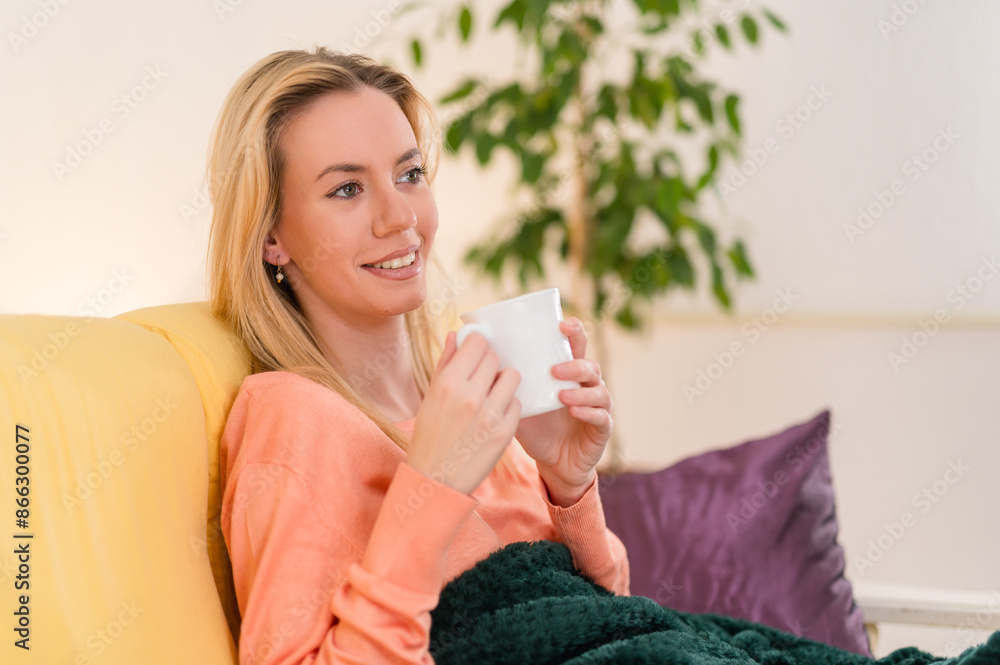 Portrait of a young atractive woman siiting on her sofa, drinking a nice cup of tea, smilling and relaxing Portrait of a young atractive woman siiting on her sofa, drinking a nice cup of tea, smilling and relaxing