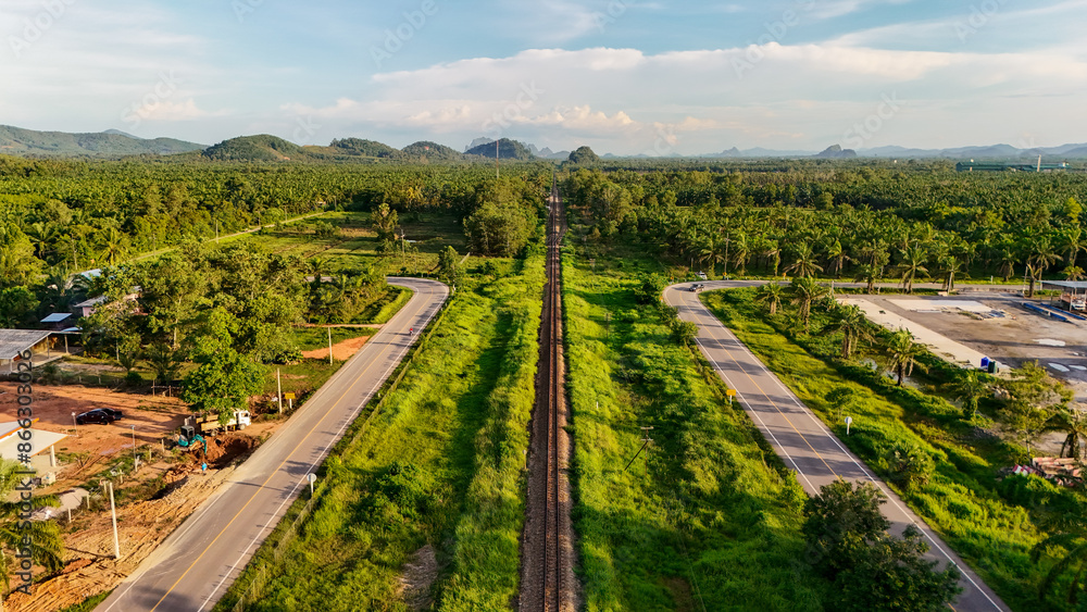 Fototapeta premium aerial view Railway tracks in the suburbs. The railway line crosses the river. Train transportation. Railway tracks and road from above that is a long way Through natural areas in rural areas