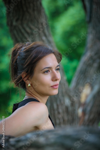 Beautiful woman posing by a tree in a picturesque park photo