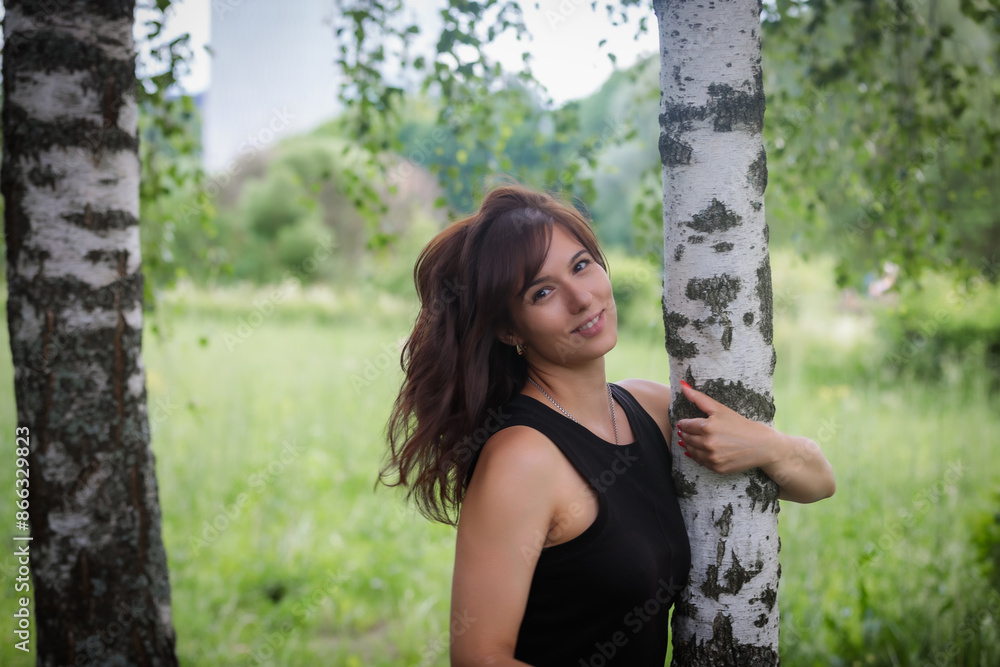 Naklejka premium Emotional woman posing in park surrounded by birch trees