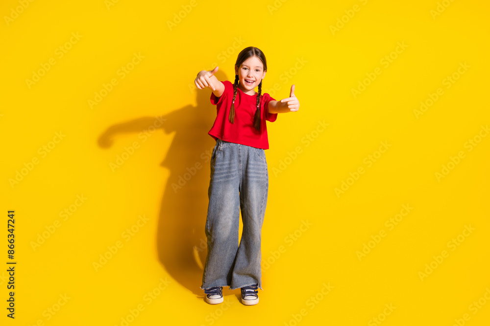 Full size photo of lovely small girl dance point fingers wear t-shirt isolated on yellow color background Full size photo of lovely small girl dance point fingers wear t-shirt isolated on yellow color background