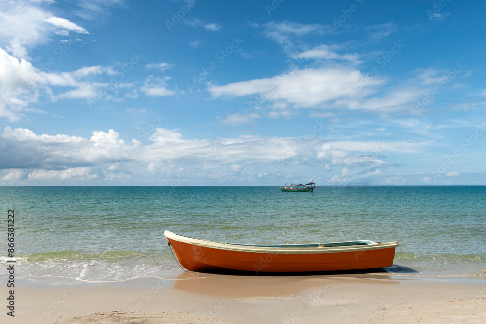 Orange boat on the shore with boat in the background