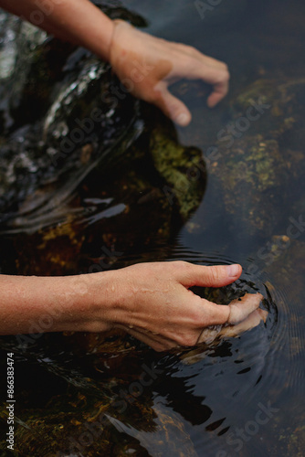 Принти на полотні Hands of woman soaked into the dark and moody water in summer