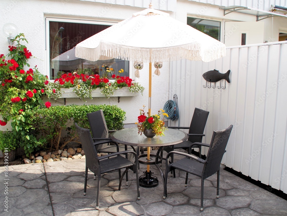 Fototapeta premium Porch with concrete pattern with table and chairs outside a house. Flower pot on the table.