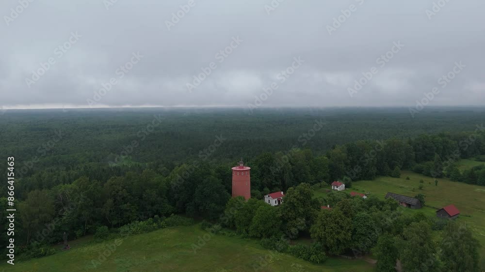Slitere Lighthouse in Latvia. Aerial View of the Baltic Sea. Slitere National Park During Cloudy Summer Day Coming Through Green Forest. Lighthouse on the West Coast of the Baltic Sea, 32 M Tower. Slitere Lighthouse in Latvia. Aerial View of the Baltic Sea. Slitere National Park During Cloudy Summer Day Coming Through Green Forest. Lighthouse on the West Coast of the Baltic Sea, 32 M Tower.