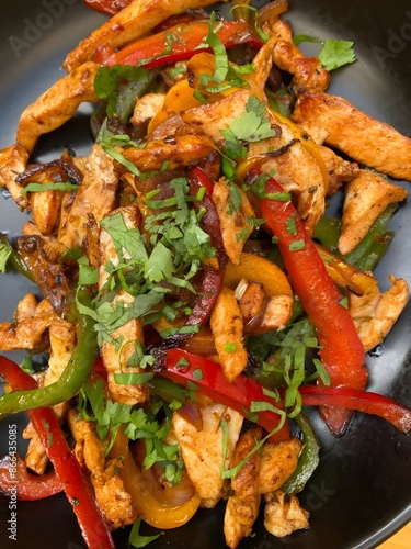 Fajitas Chicken meat, sliced bell pepper, and parsley in a frying pan.