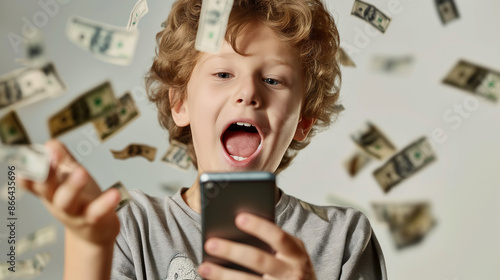 Young boy amazed by digital money flurry from smartphone. Earning money using the internet. photo