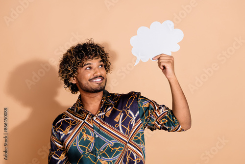 Photo portrait of handsome young male hold look paper cloud dressed stylish print garment isolated on beige color background photo